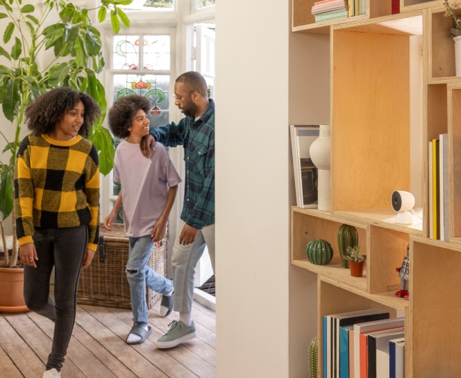 Father and children in home with Indoor Google Nest Cam on bookshelf