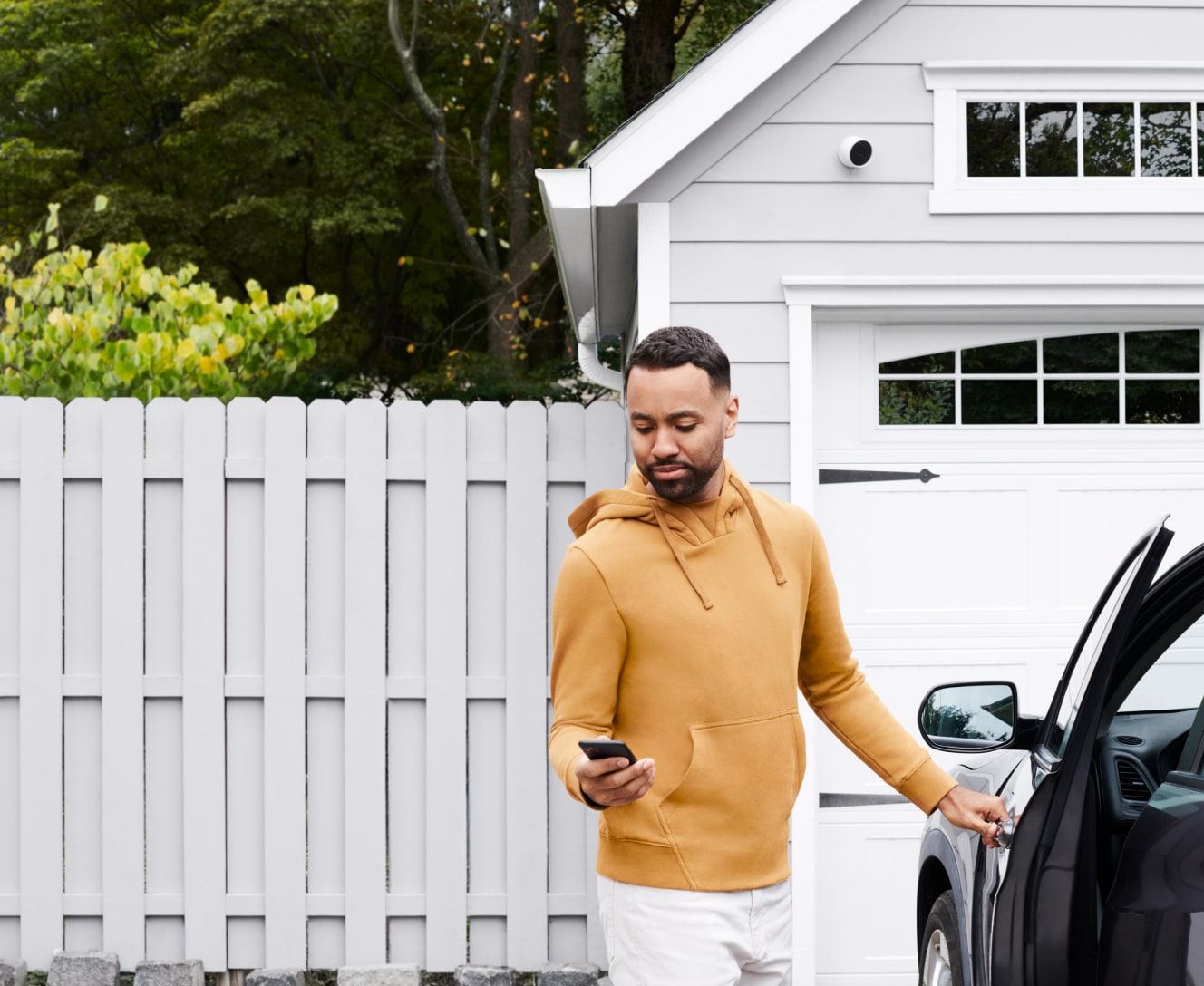 Man in driveway using his phone to check ADT survelliance on the ADT app