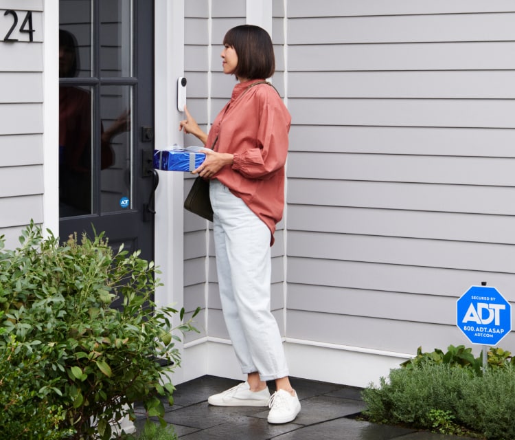 Women ringing the Google Nest Doorbell and carrying a gift