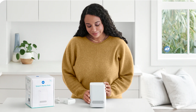 Women setting up an ADT device and smiling Women setting up an ADT device and smiling
