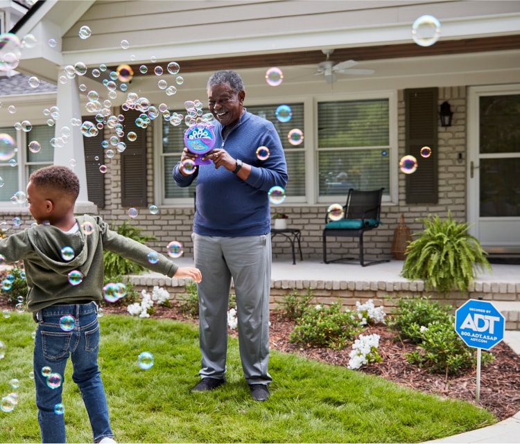 Family playing in the front yard in front of an ADT protected house 