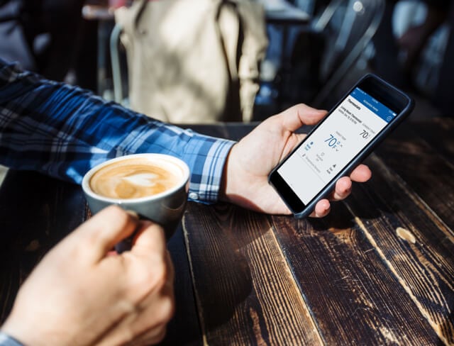 Person using ADT home security app and drinking coffee Person using ADT home security app and drinking coffee