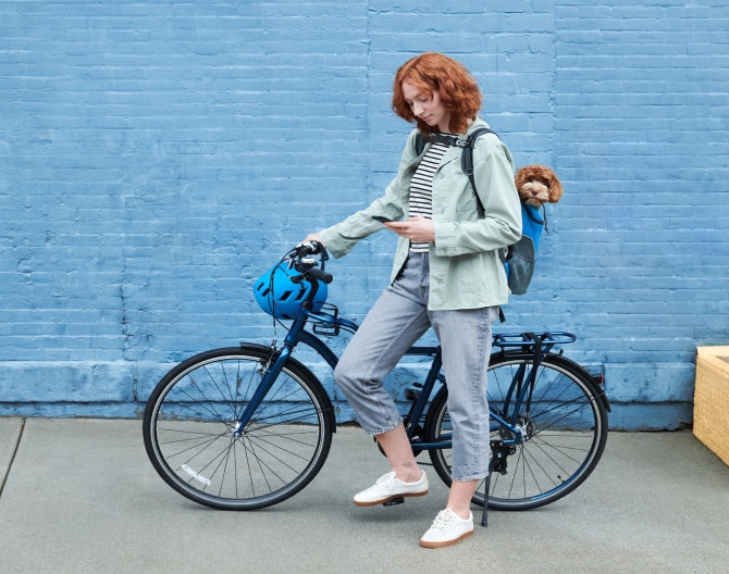 Woman on a bike checking her ADT app on her phone Woman on a bike checking her ADT app on her phone