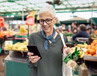 Woman using the ADT app on her phone in the grocery store Woman using the ADT app on her phone in the grocery store
