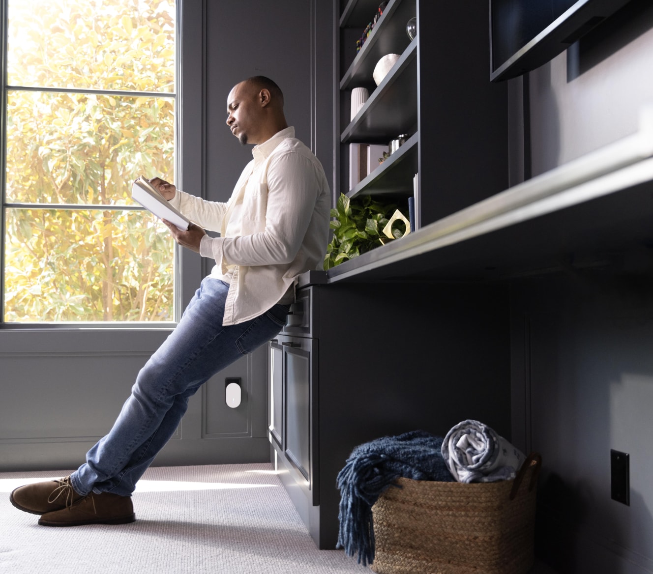 Man reading a book with the ADT Alarm Range Extender plugged in