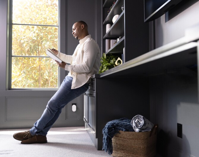 Man reading a book with the ADT Alarm Range Extender plugged in