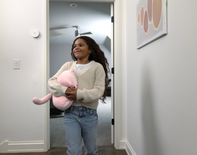 Niño entrando a su casa con una sirena interior ADT en la pared Niño entrando a su casa con una sirena interior ADT en la pared