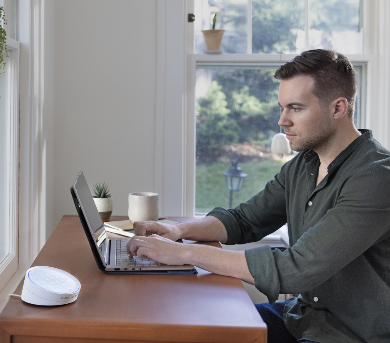 Man working on his laptop at a table with the ADT Keypad next to him Man working on his laptop at a table with the ADT Keypad next to him