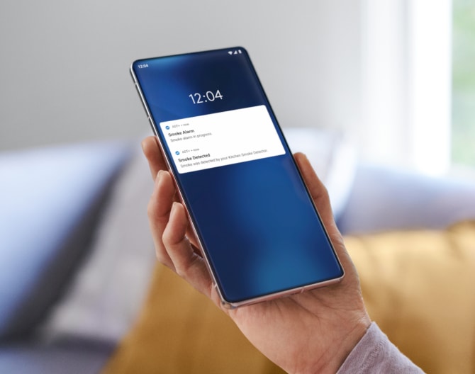 Hand holding a phone checking notifications from the ADT app Hand holding a phone checking notifications from the ADT app