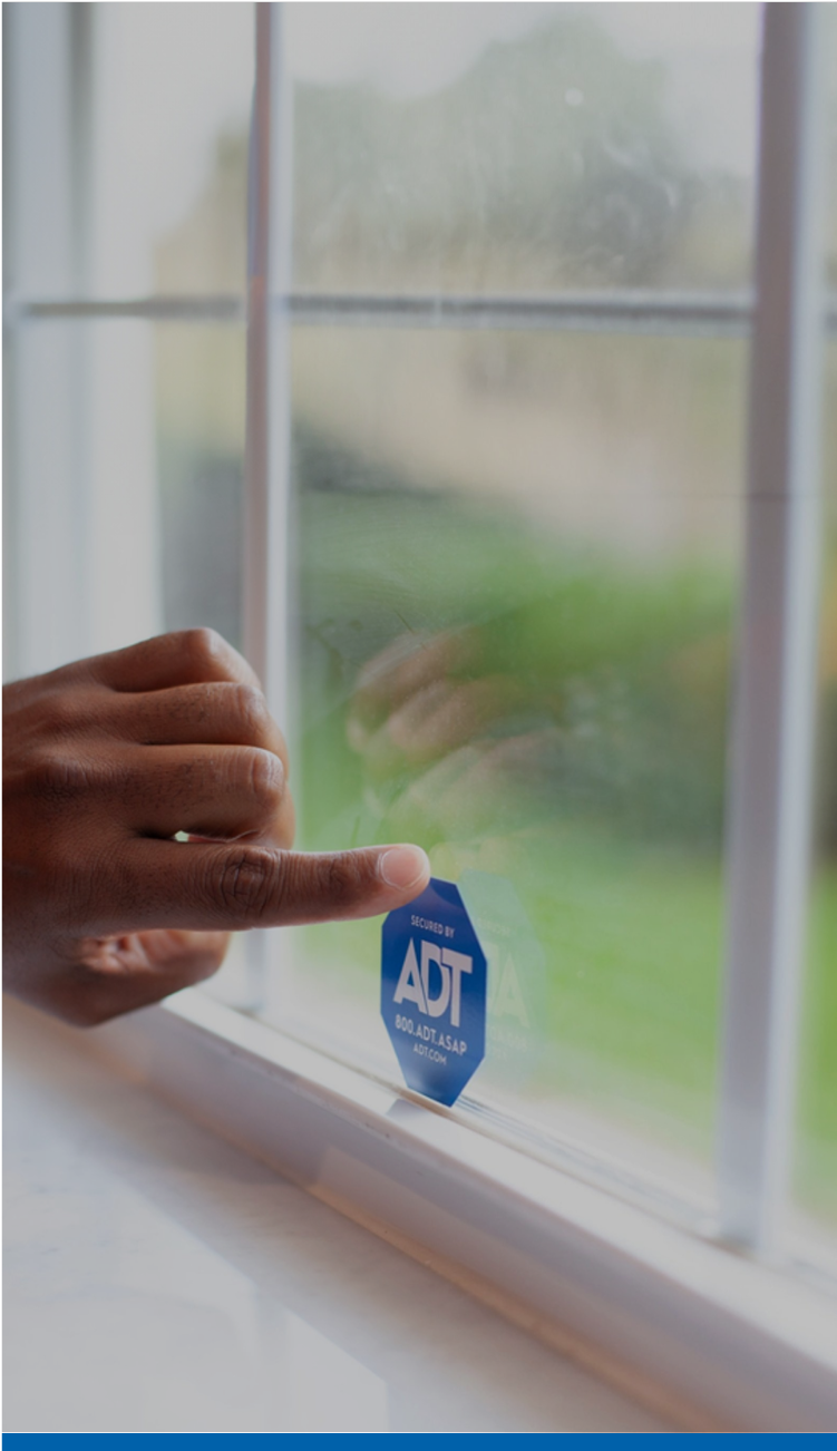 Hand putting an ADT window sticker on a window