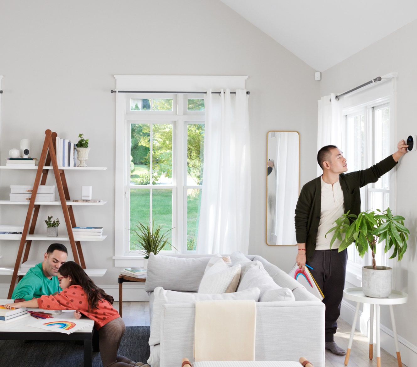 Family sitting in their living room while someone adjusts the Google Nest Cam (Indoor)