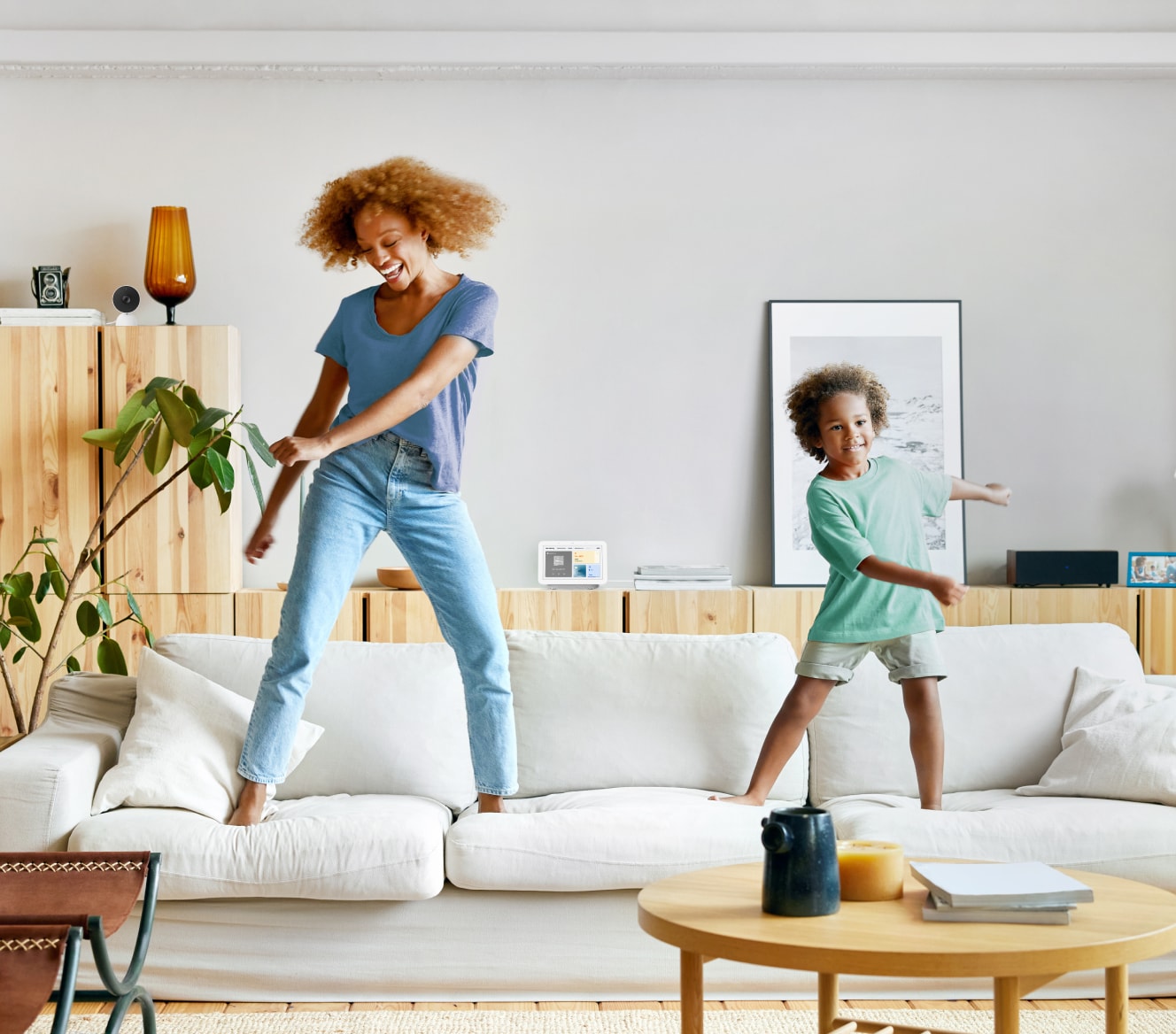 Women and her child jumping on the couch with the Google Nest Hub 2 Gen in the background Women and her child jumping on the couch with the Google Nest Hub 2 Gen in the background