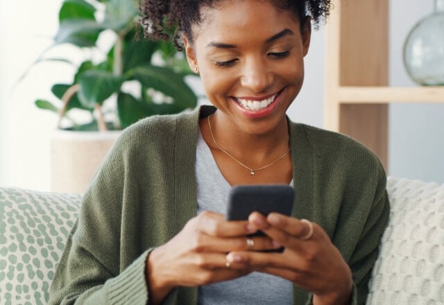 Woman smiling and looking at her cell phone.