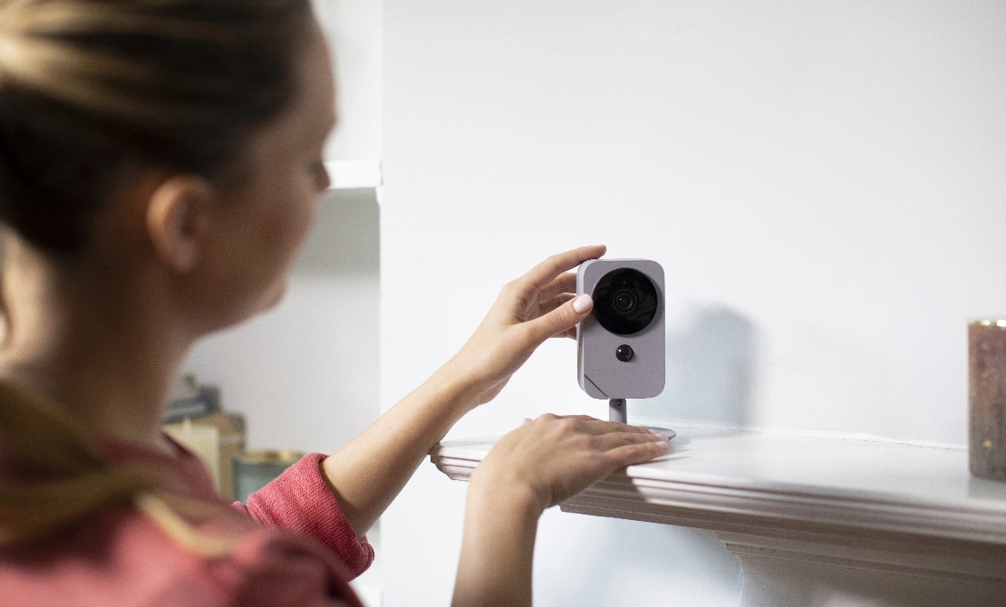 Woman self installing an ADT indoor camera on a shelf in her home