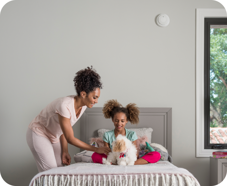 Mother and her child with ADT smoke detector on wall