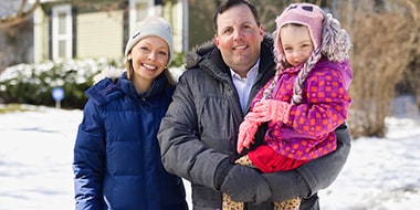 Image of three family members outside their home on a snowy day  Image of three family members outside their home on a snowy day