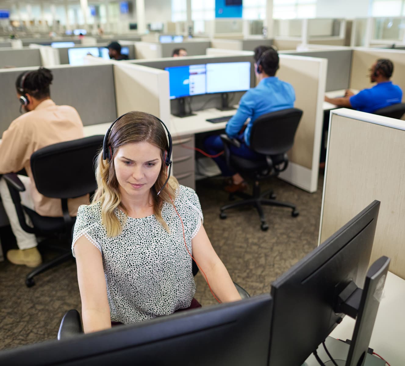 ADT customer service rep in the ADT call center typing on her computer and troubleshooting with a customer on her headset 